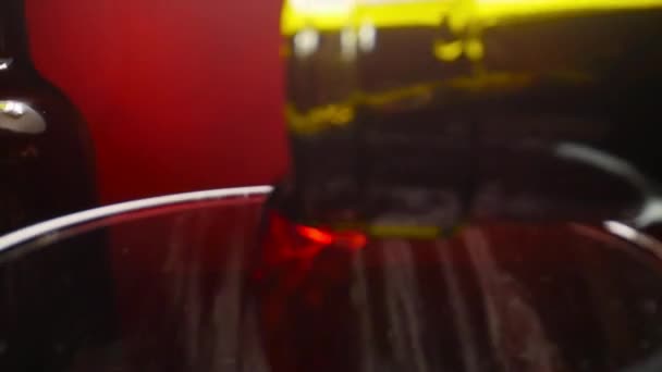 Κόκκινο κρασί ρίχνει σε ένα ποτήρι κρασί σε κόκκινο φόντο σε αργή κίνηση — Αρχείο Βίντεο