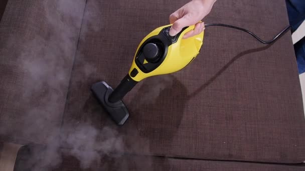 Furniture and apartment cleaning concept. Man cleaning couch with steam cleaner at home — 비디오