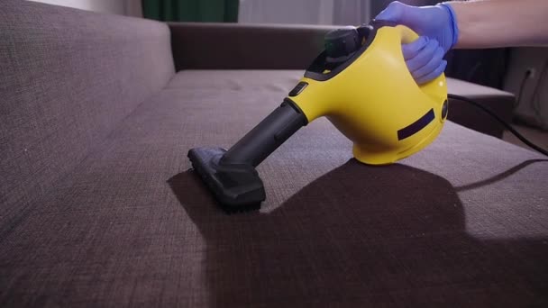 Furniture and apartment cleaning concept. Man cleaning couch with steam cleaner at home — 비디오