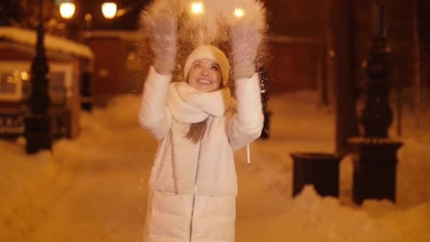 Jeune fille heureuse jette de la neige sur une rue de la ville de nuit — Video