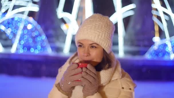 Jong gelukkig vrouw drinkt koffie of glühwein buiten in de winter in kerst decoraties — Stockvideo