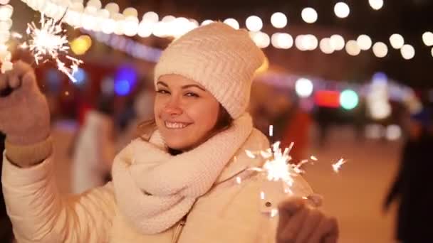 Concepto de vacaciones de invierno. Joven hermosa chica sonriente feliz sosteniendo chispas — Vídeos de Stock