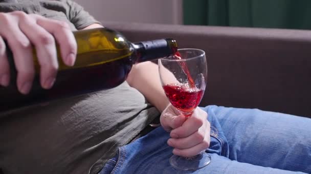 Un hombre en el sofá vierte vino — Vídeos de Stock