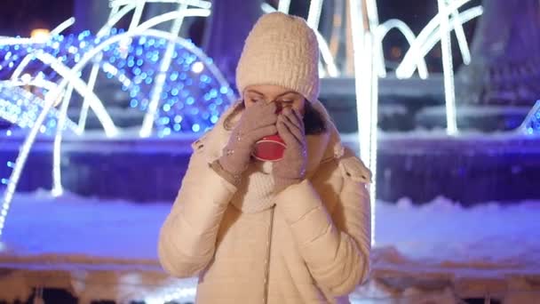Joven feliz mujer bebe café o vino caliente al aire libre en invierno en decoraciones de Navidad — Vídeo de stock