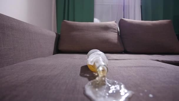 Concepto de contaminación y limpieza. Un vaso de cerveza cae en el sofá — Vídeos de Stock
