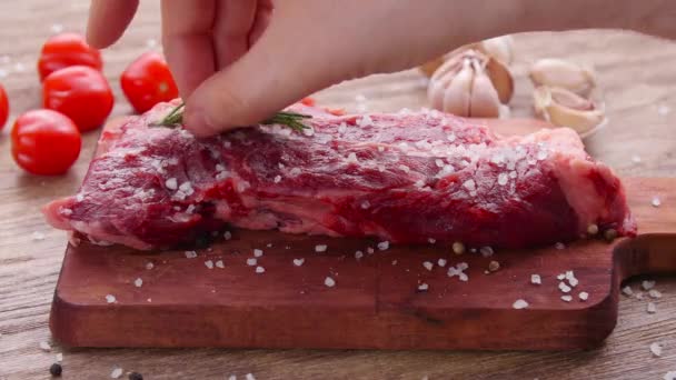 Rohes Frischfleisch-Steak mit Kräutern und Gewürzen auf rustikalem Hintergrund — Stockvideo