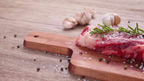 Концепція приготування їжі. Сирий яловичий стейк на дерев'яному столі . — стокове відео