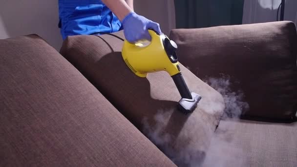 Conceito de limpeza de móveis. Limpar o sofá com um limpador de vapor antibacteriano — Vídeo de Stock
