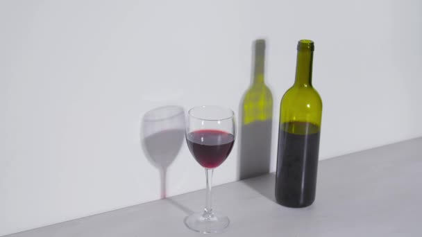 Foto conceptual, una botella de vino y una copa sobre un fondo blanco — Vídeos de Stock