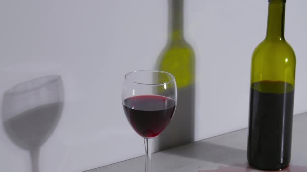 Концептуальный снимок, бутылка вина и бокал на белом фоне — стоковое видео