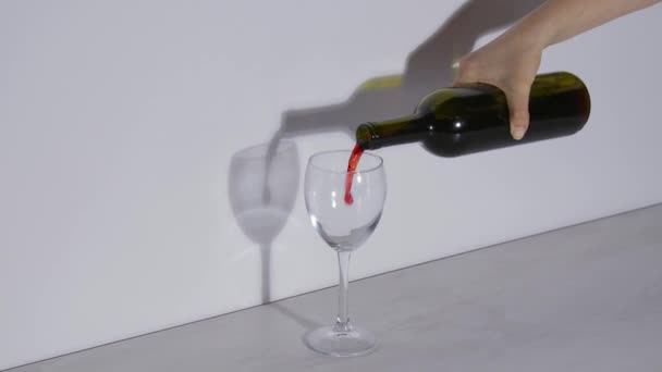 Conceptual shot, pouring red wine into a glass on a gray background — Stockvideo