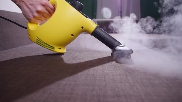 Mobili e appartamento concetto di pulizia. Uomo pulizia divano con pulitore a vapore a casa — Video Stock