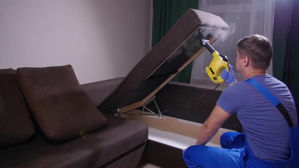 Möbel- und Wohnungsreinigungskonzept. Mann putzt Couch zu Hause mit Dampfreiniger — Stockvideo