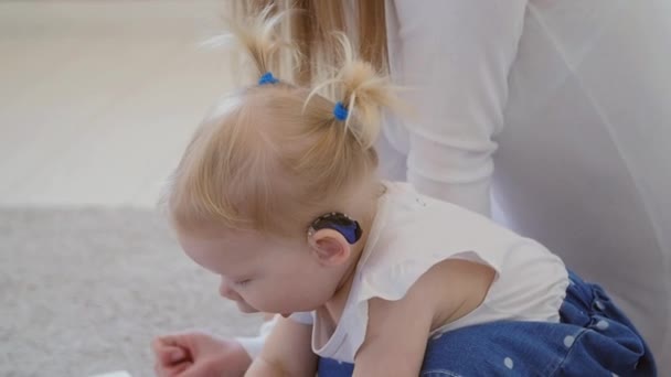 Concepto de discapacidad auditiva y su tratamiento. Linda niña con un audífono — Vídeos de Stock