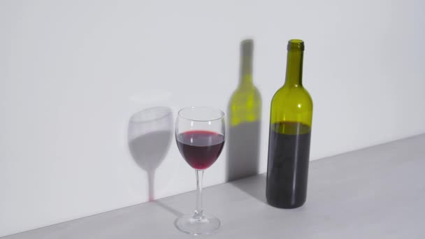 Conceptuele shot, een fles wijn en een glas op een witte achtergrond — Stockvideo