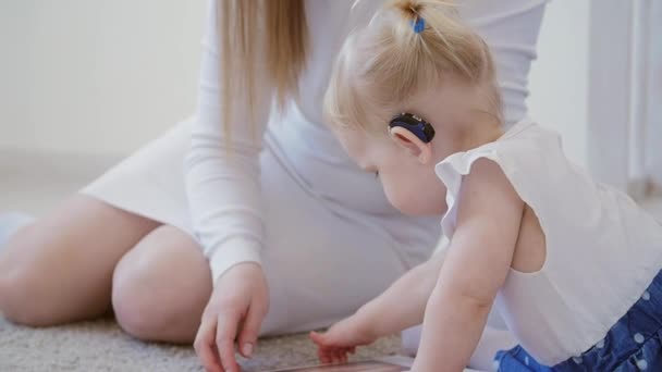 Concepto de discapacidad auditiva y su tratamiento. Linda niña con un audífono — Vídeos de Stock