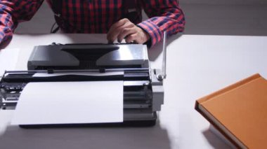 Yazarlar gün kavramı. Karanlık bir odada bir daktiloda yazmaya genç erkek yazar