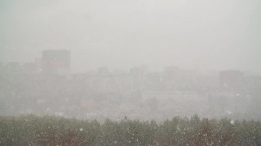 Şehrin üzerine ağır çekimde kar yağar.