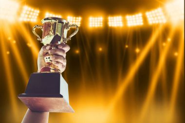 Man holding up a gold trophy cup,win concept. clipart