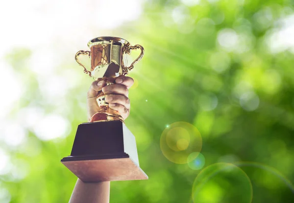 Hombre sosteniendo una copa de trofeo de oro, concepto de victoria . — Foto de Stock