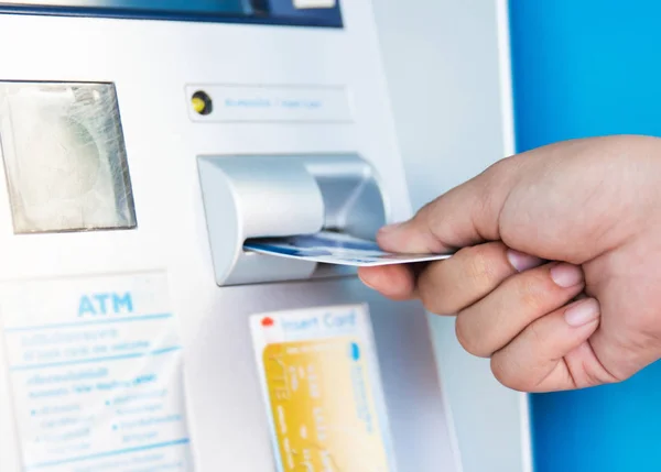 female hand inserting ATM card into bank machine to withdraw mon