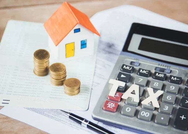 Model house with tax words,money,calculator and tax papers.