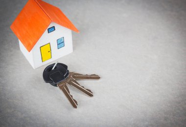 Çimento arka planında anahtar olan turuncu ev.