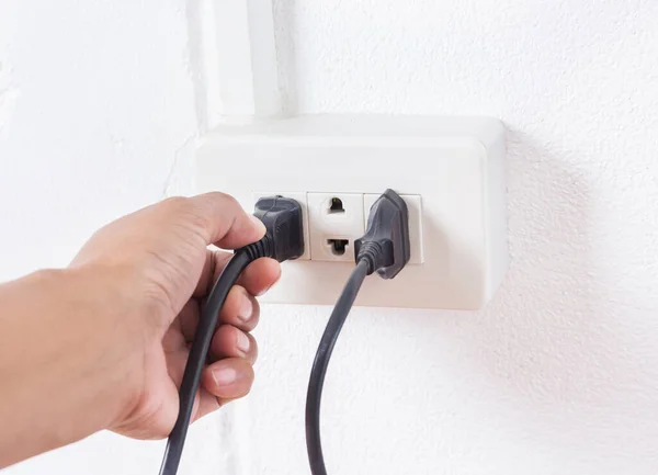 Hand holding electric power plug.