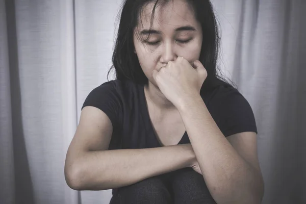 Sad woman sitting alone in room