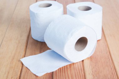 Beyaz tuvalet kağıdı ahşap masada yuvarlanıyor..