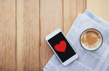 Kalbi ve akıllı telefonu olan bir fincan kahve, sevgililer günü konsepti..