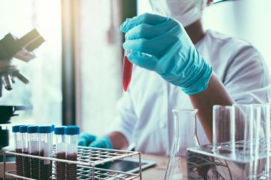 Laboratuvar araştırması için elinde test tüpleri tutan bir bilim adamı..