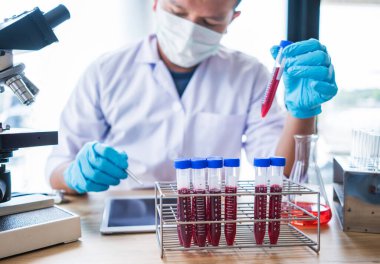 Laboratuvar araştırması için elinde test tüpleri tutan bir bilim adamı..