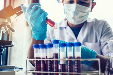 Laboratuvar araştırması için elinde test tüpleri tutan bir bilim adamı..