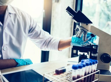 Laboratuvar araştırması için elinde test tüpleri tutan bir bilim adamı..