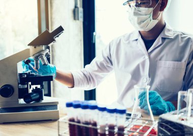 Laboratuvar araştırması için elinde test tüpleri tutan bir bilim adamı.