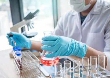 Laboratuvar araştırması için elinde test tüpleri tutan bir bilim adamı..