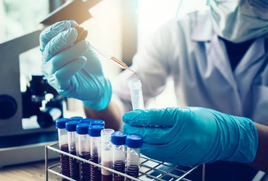 Laboratuvar araştırması için elinde test tüpleri tutan bir bilim adamı.