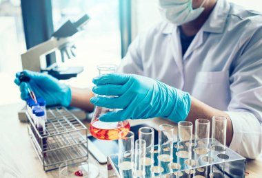 Laboratuvar araştırması için elinde test tüpleri tutan bir bilim adamı..