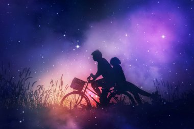Romantic couple in love with their bicycle on field,dreaming about the stars in night sky.