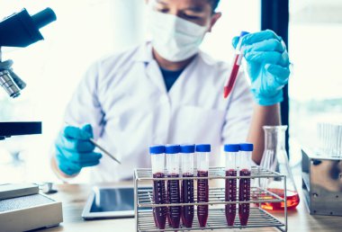 Laboratuvar araştırması için elinde test tüpleri tutan bir bilim adamı..