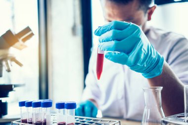 Laboratuvar araştırması için elinde test tüpleri tutan bir bilim adamı..