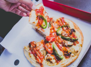 Ellerin karton bir kutuda pizzayı dilimlediği yakın plan..