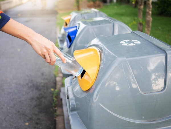 Женщина держит пластиковую бутылку в корзине для переработки концепции повторного использования
.