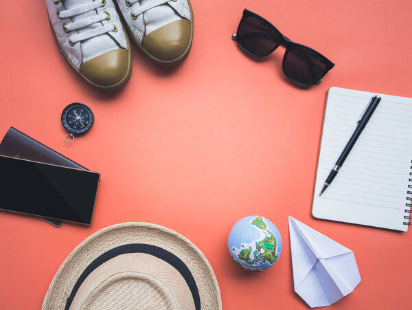 Аксессуары для путешествий, отдых в путешествии, туризм макет смартфона, компас, шляпа, обувь, солнцезащитные очки, паспорт, бумажный самолет, записная книжка на оранжевой бумаге
