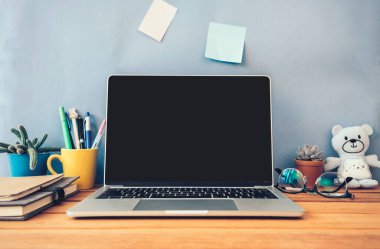 Laptop bilgisayarı, ofis malzemeleri, kitaplar, gözlük, kaktüs, bebek, masayı düzenle.