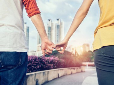 Sevgililer Günü arkaplanı. Gün batımında yürürken el ele tutuşan mutlu çift..