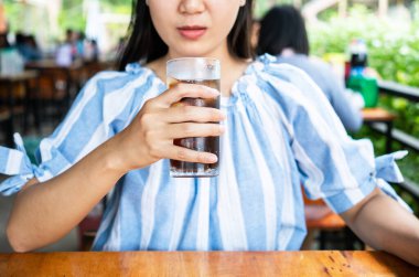 Bir bardak buzlu kola içen kadın..