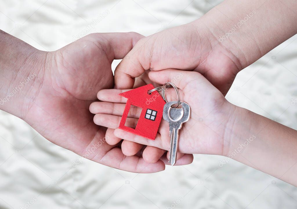 Real estate and family home concept ,hands holding a house key. 