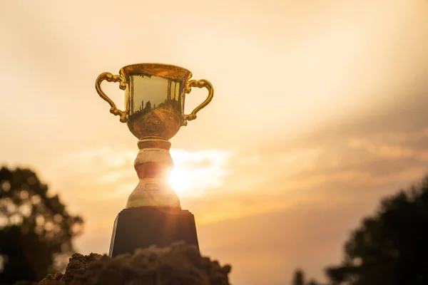 Win concept,Gold trophy cup on top mountain with sunrise sky background.